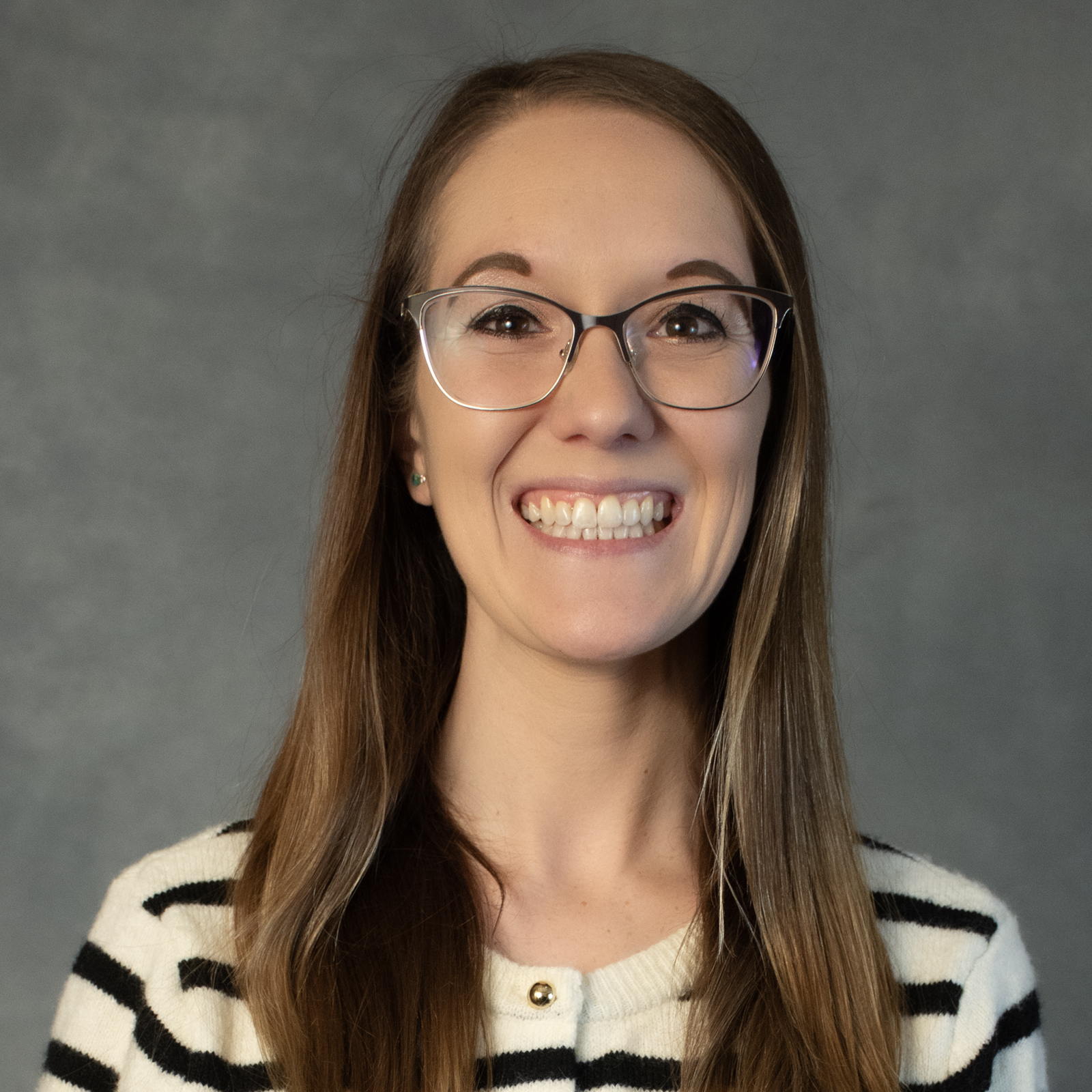 Woman with long brown hair wearing glasses and striped top