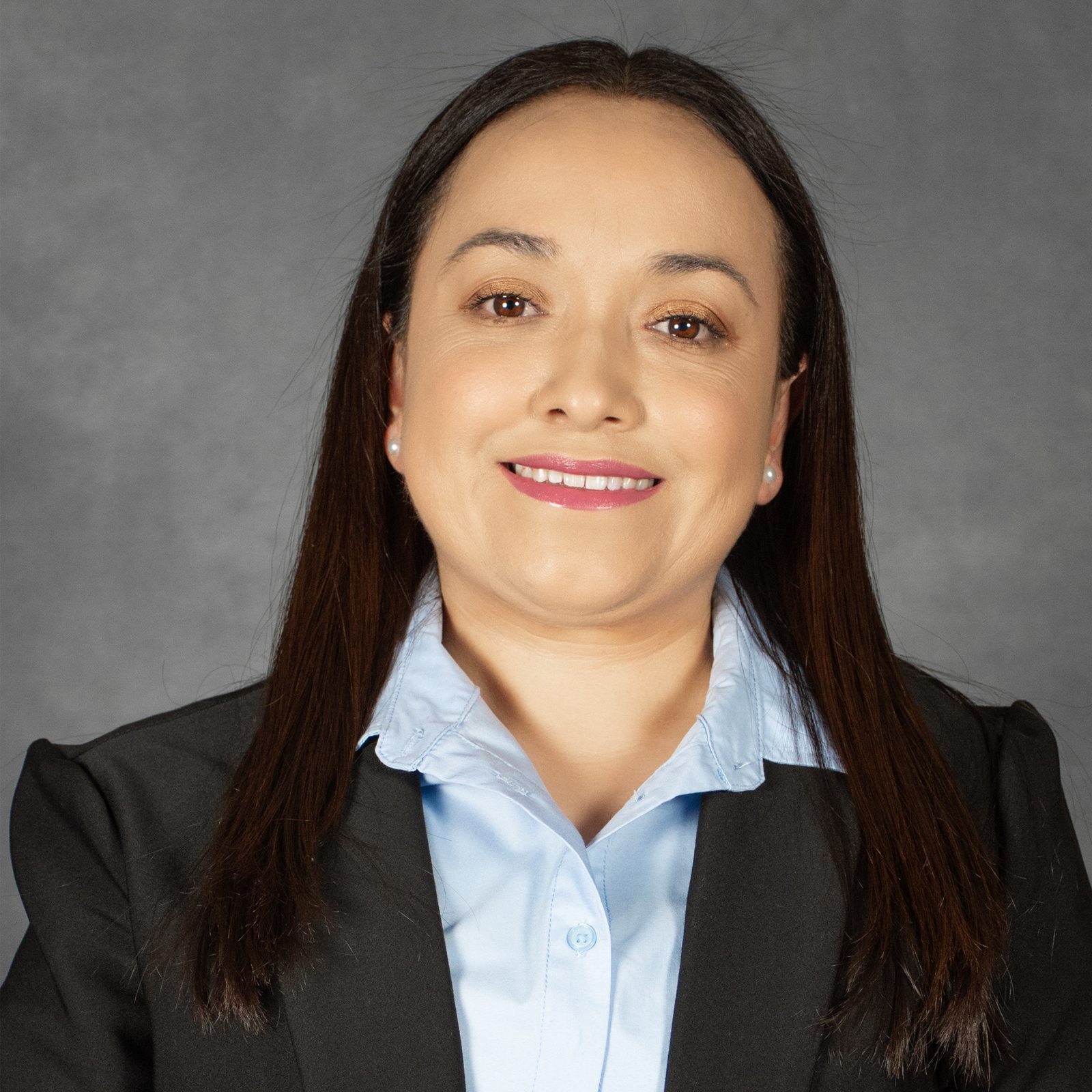 Woman with long dark hair wearing black jacket with light blue collared shirt