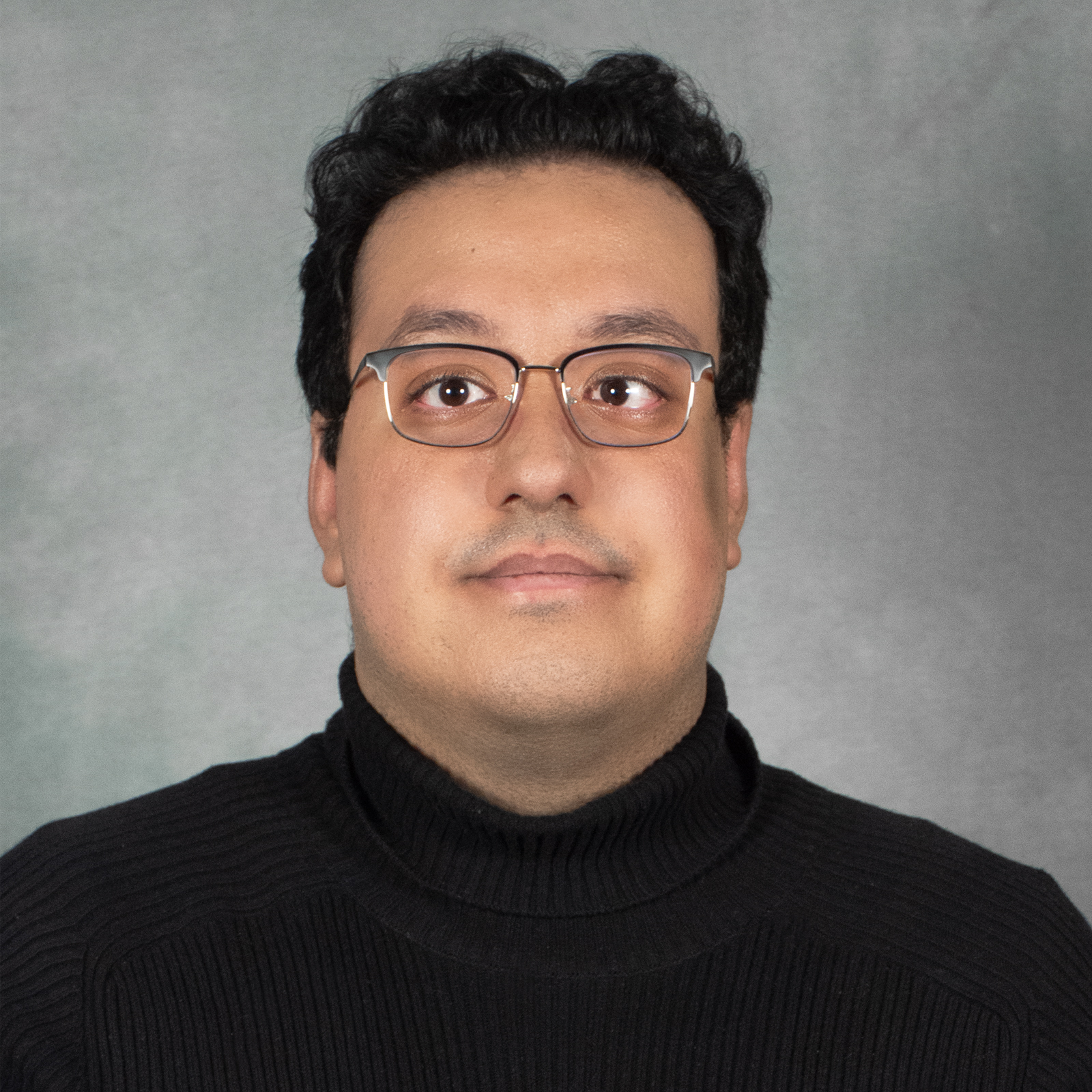 Man with short dark hair wearing glasses and a black turtleneck sweater
