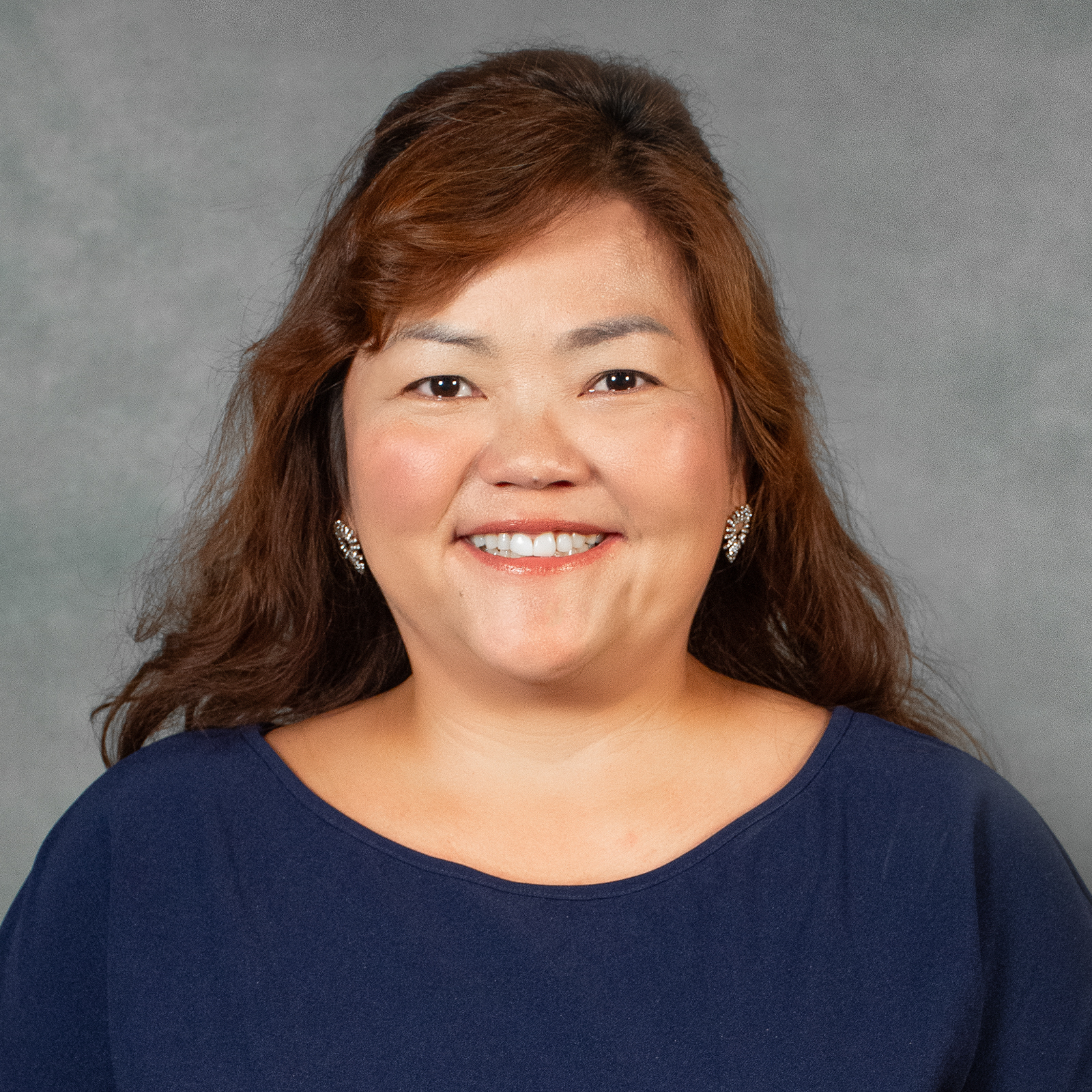 Woman with auburn shoulder length hair wearing dark blue dress