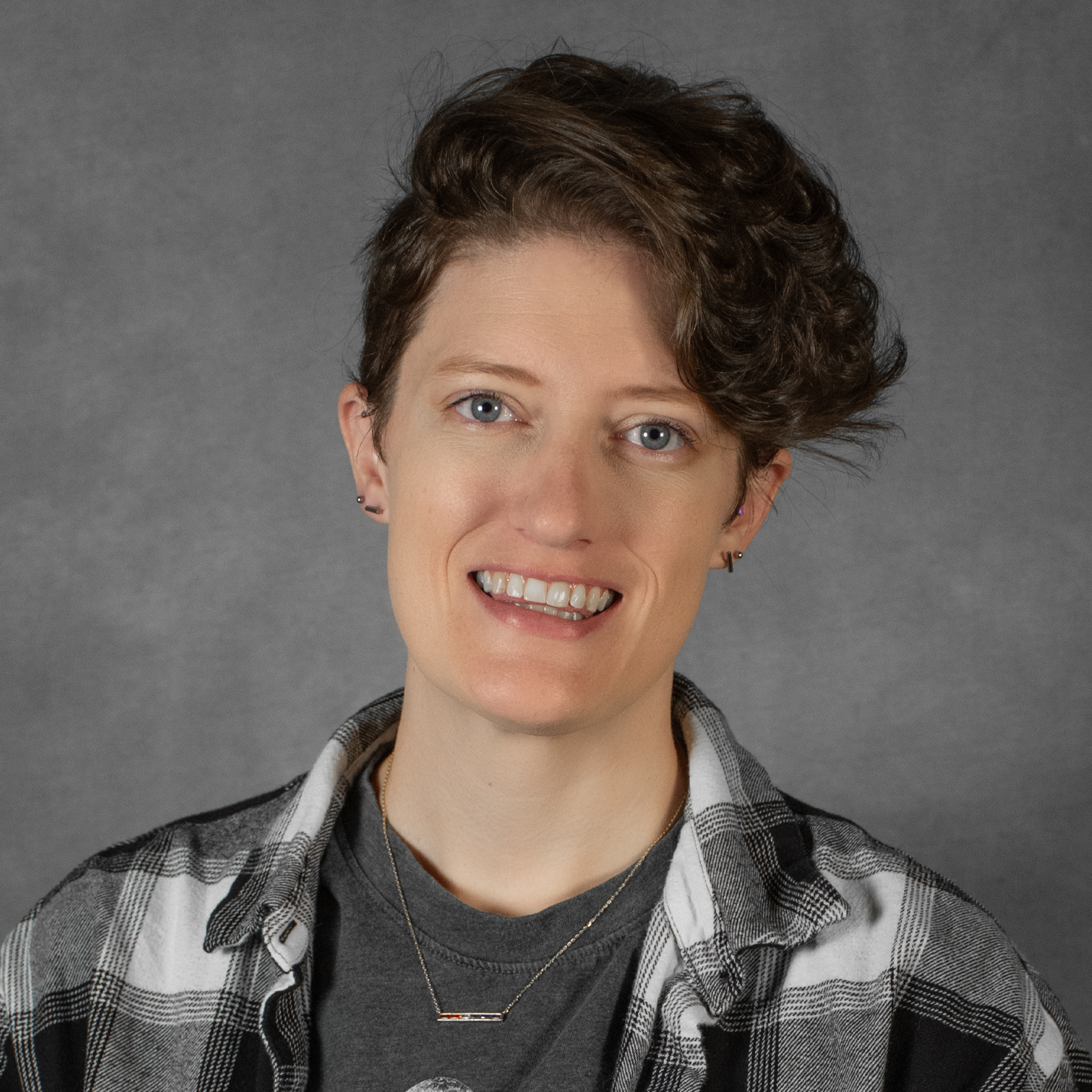 Woman with wavy short brown hair wearing plaid shirt