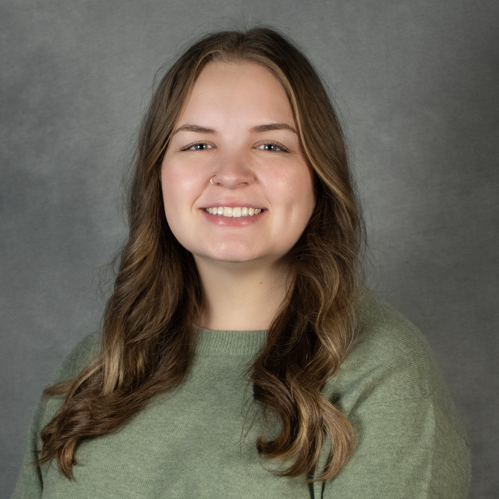 Woman with long brown hair wearing a green top