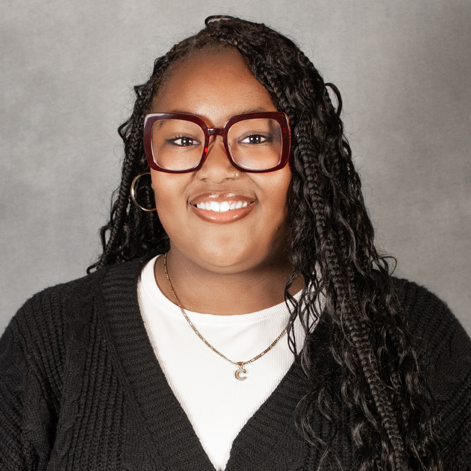 woman with long Brunette braids wearing red glasses and black sweater