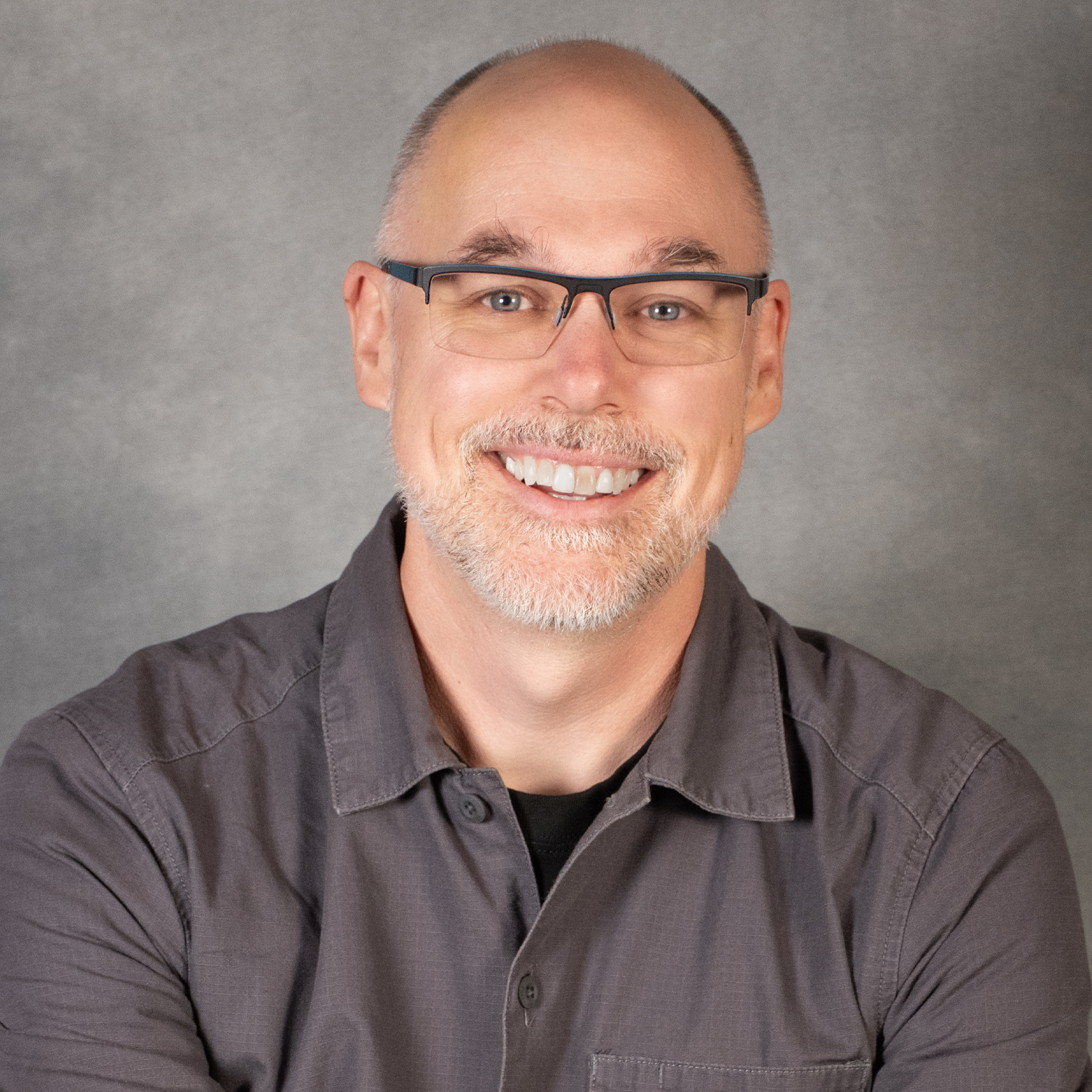 Man with short beard and hair wearing glasses and a gray shirt