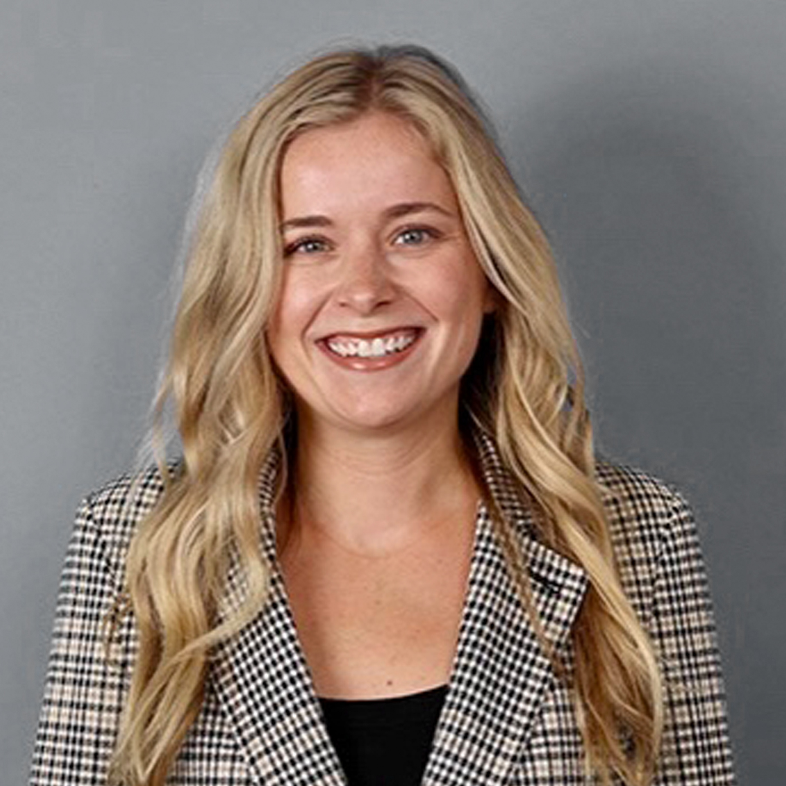 Headshot of blonde women in gray jacket with a gray background