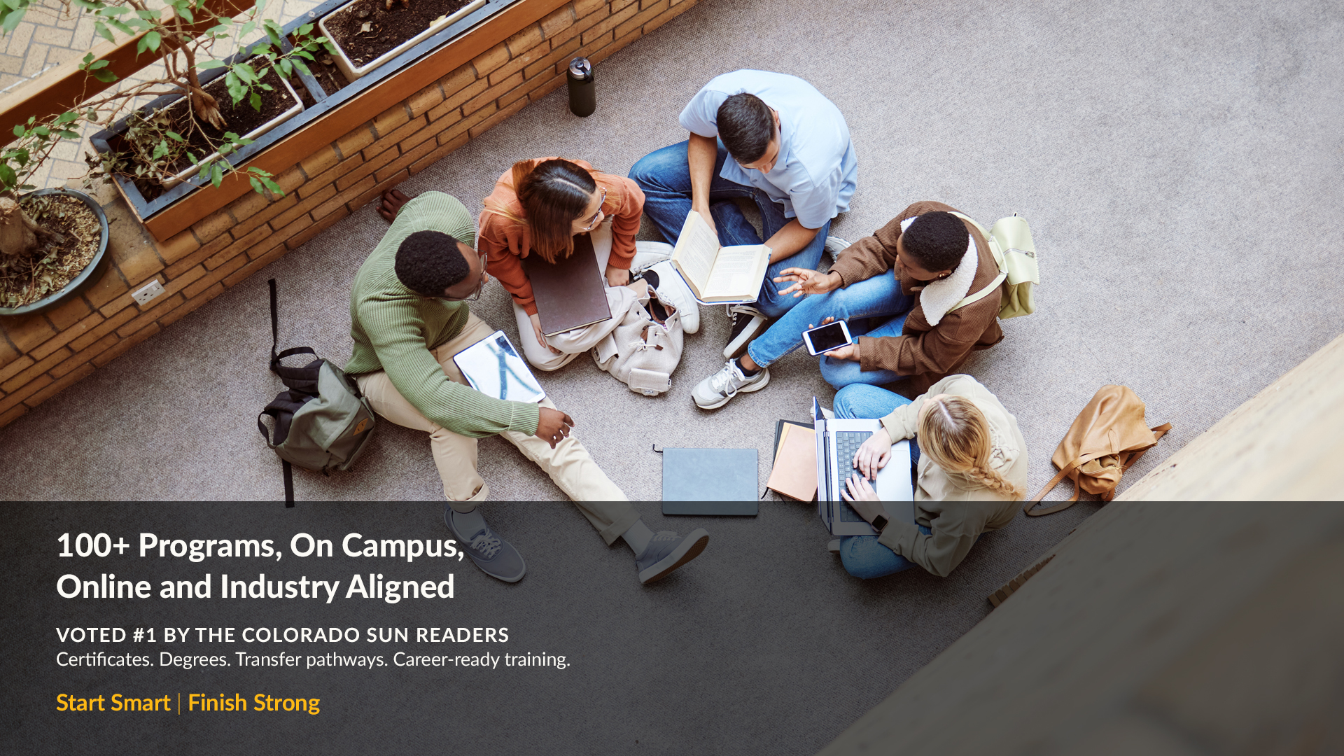 Group of 5 students sitting on the ground talking 