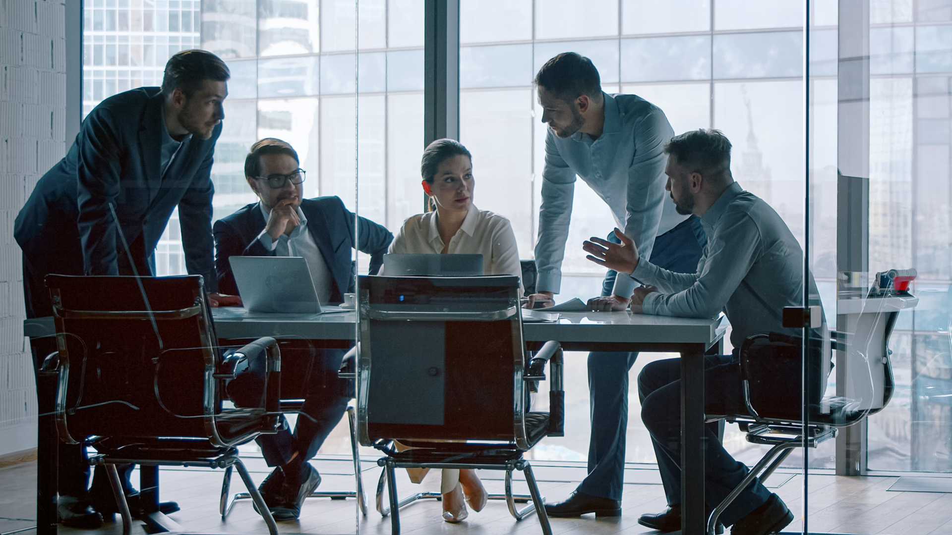 Stock image of 5 people in a dark room having a meeting 
