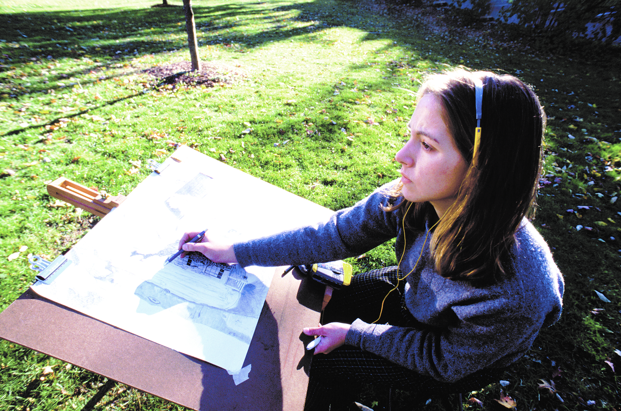 CCD students often take advantage of the Auraria Campus' beauty and present their work on campus often. image of a female CCD student drawing on a large papaer outside on campus
