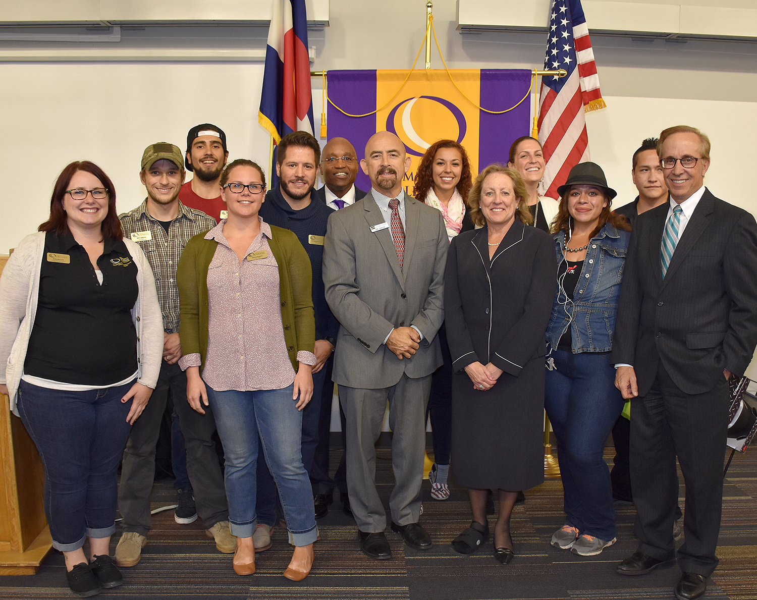CCD students, faculty, and staff pose with Colorado Lt Gov Joe Garcia at the Advanced Manufacturing Center's Grand Opening group of faculty and students in front of CCD flag
