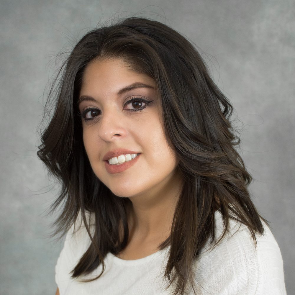 Young female with black wavy hair in white shirt.