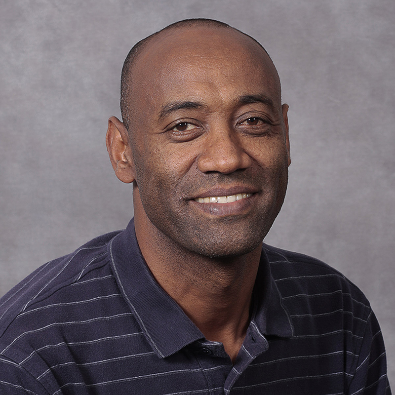 Man wearing a black striped shirt smiling.