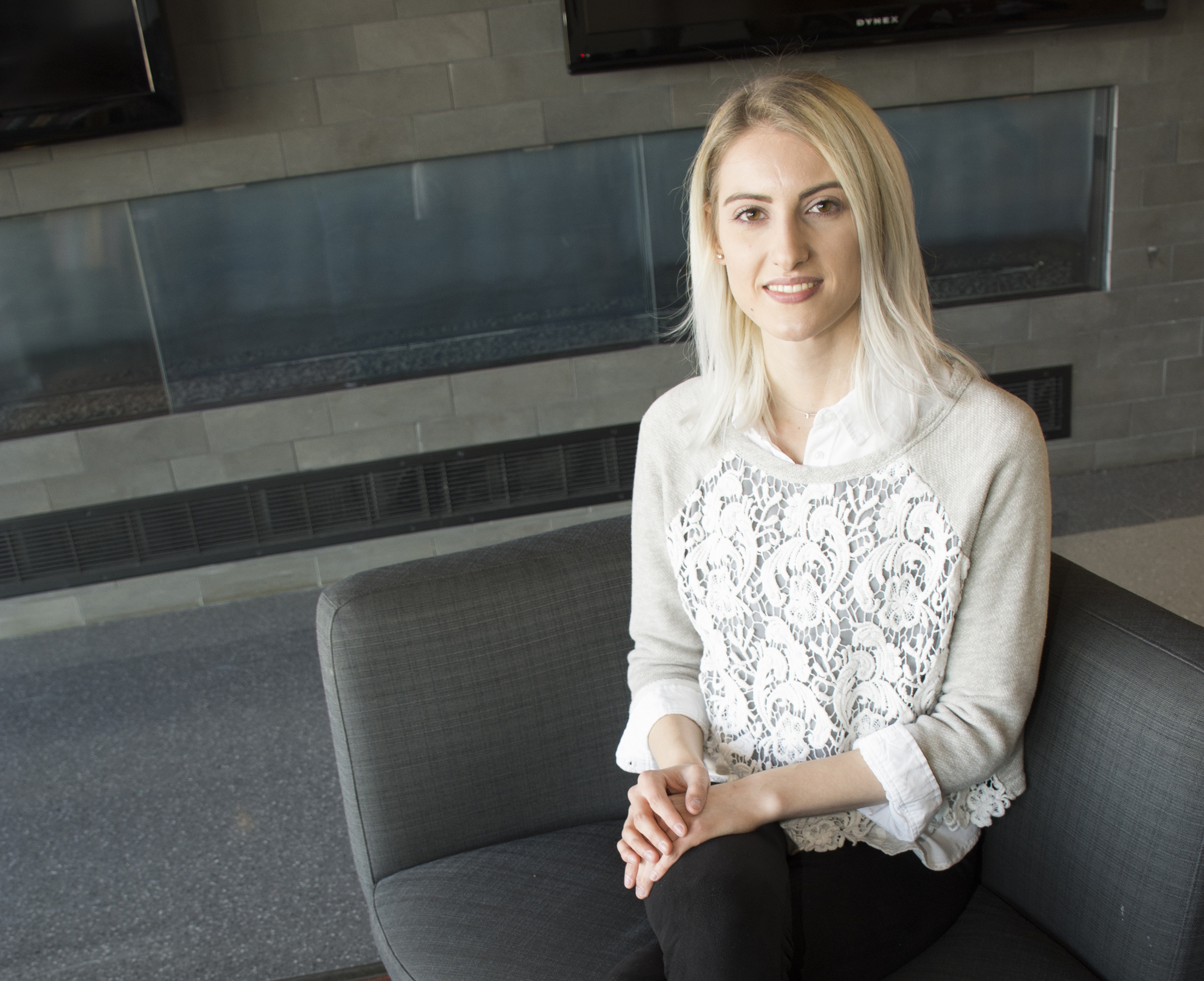 Woman with blond hair sitting in a black chair smiling