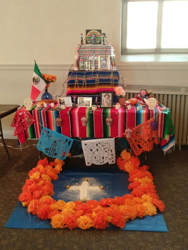 Dia De Los Muertos Alter with orange flowers and many decorative items