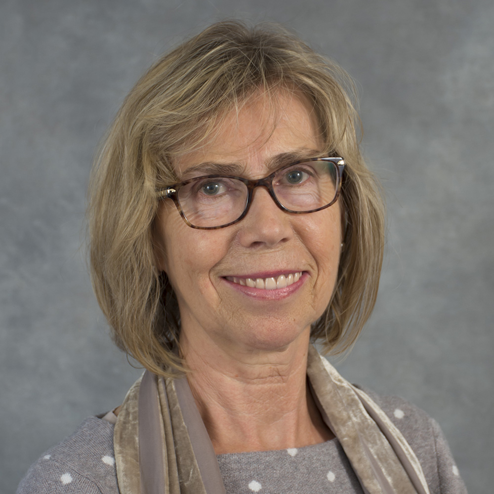 Woman with glasses wearing a gray shirt with white polka dots.