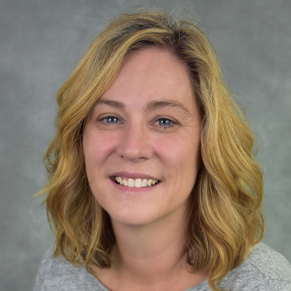 Woman with a short blonde hair smiling.