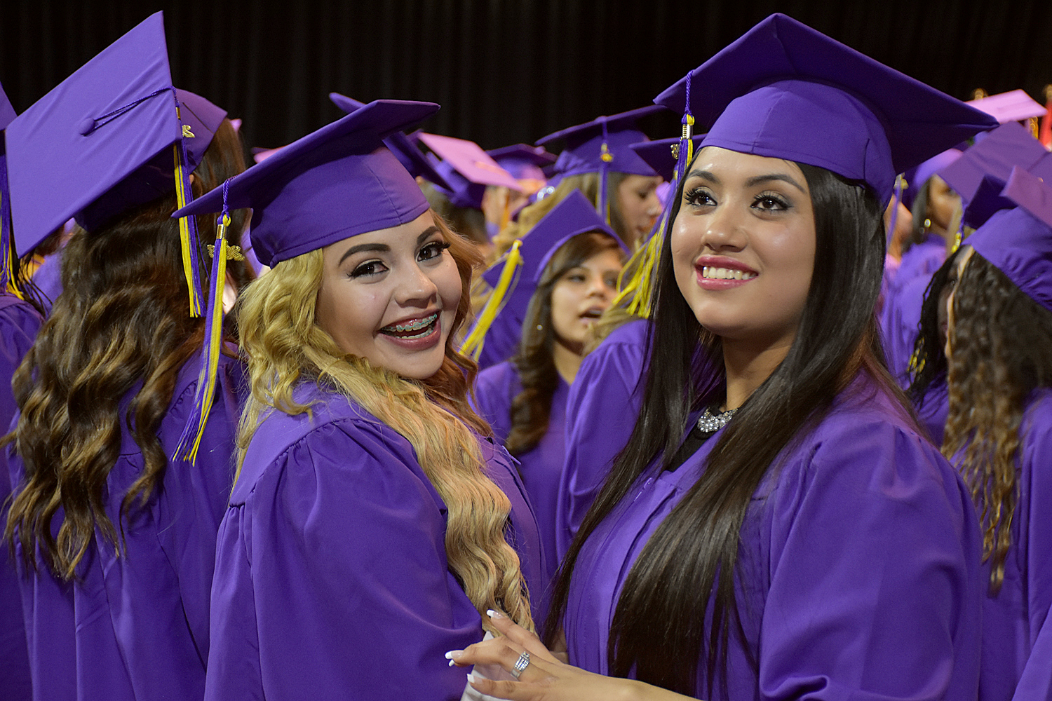 two females wearing cap and gowns at commencement