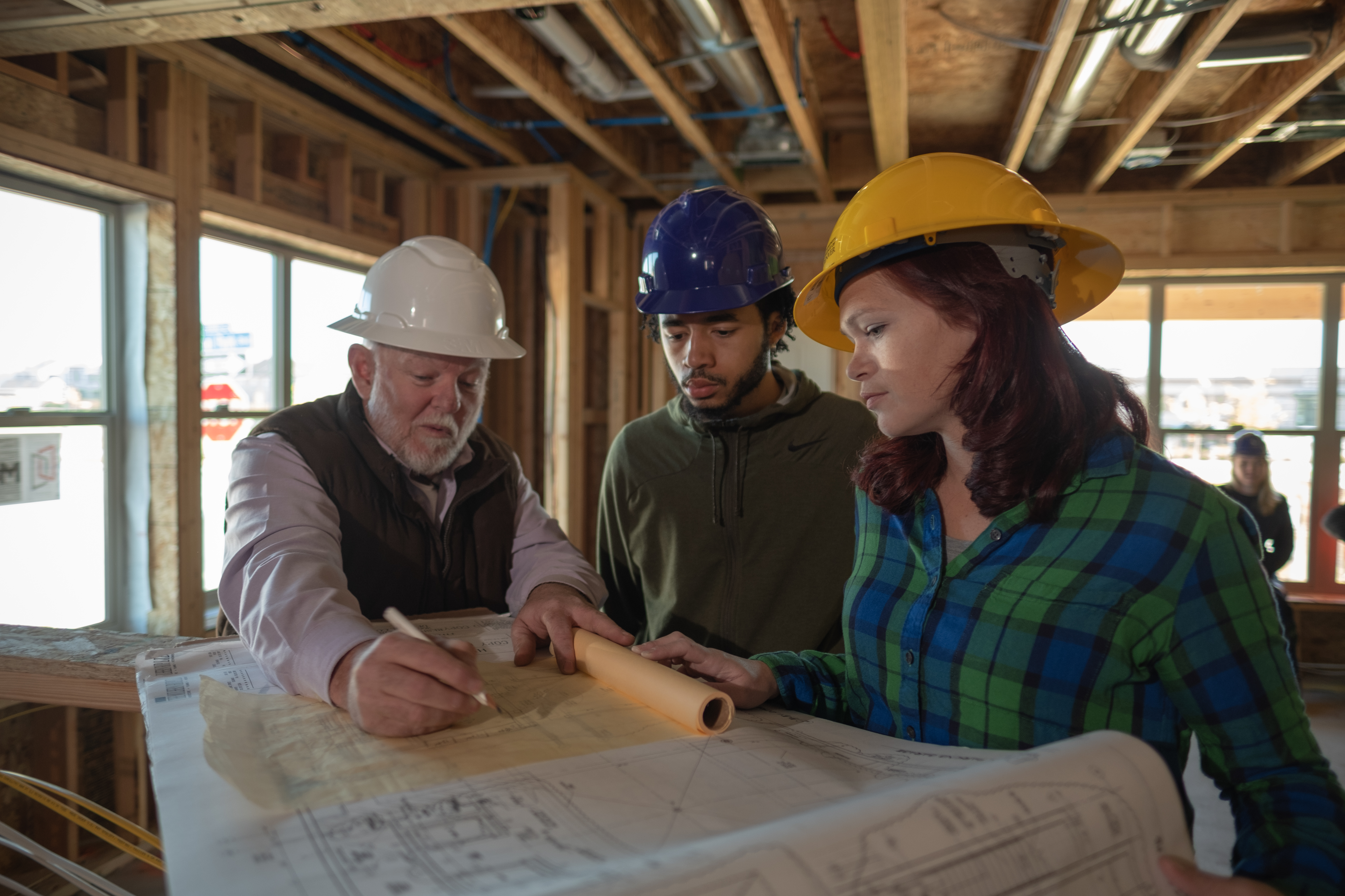Gain intensive hands-on construction skills and experience. two students with professor at a construction site