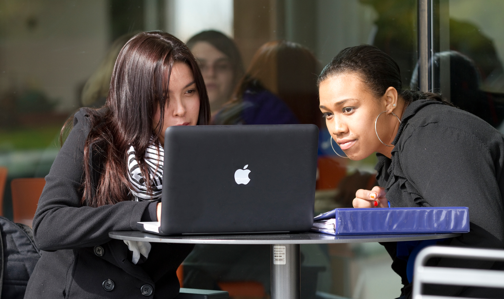 two female students work together on a computer.