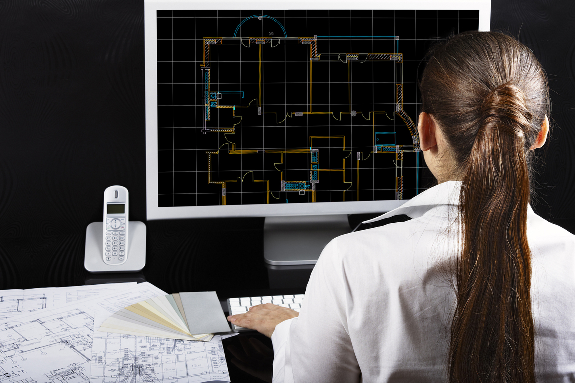 Woman using architectural drafting software on a computer with a big screen