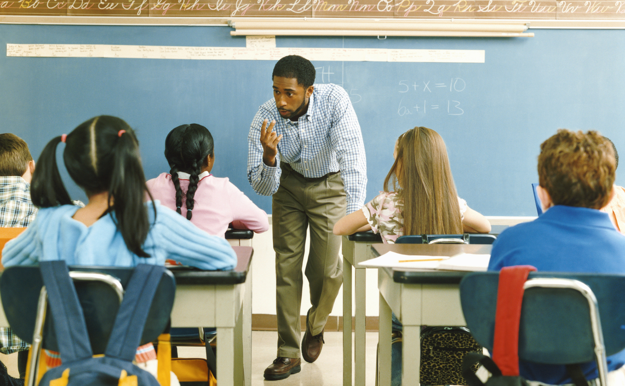 image of male elementary school teacher in front of classroom teaching