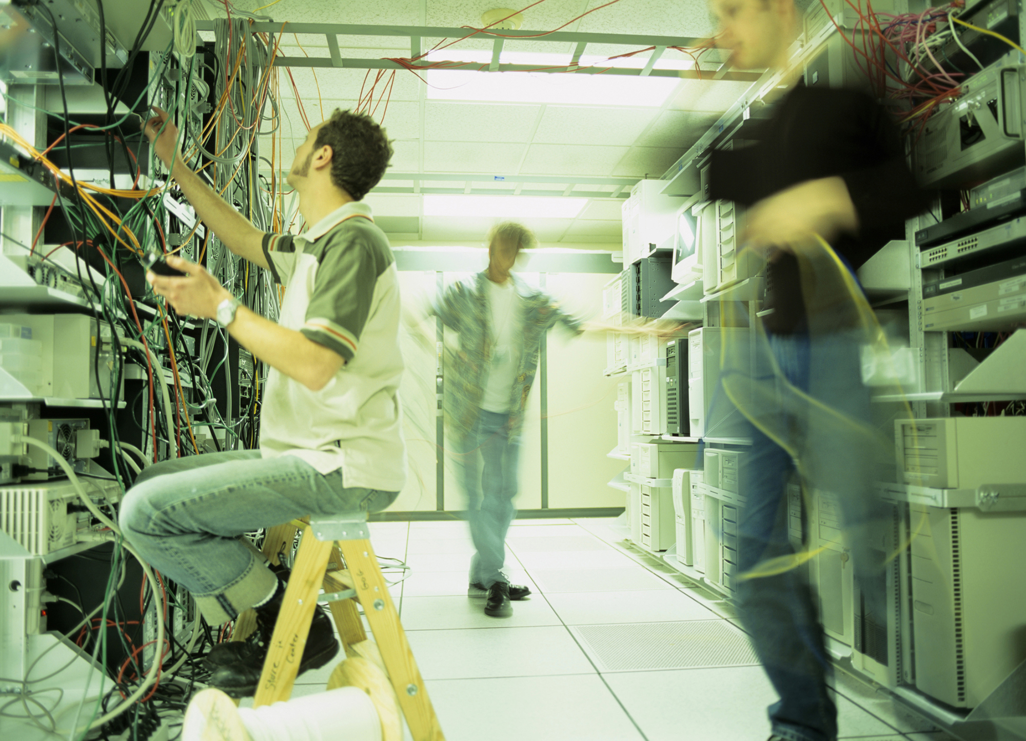 image of three people in a computer server room working on computer cables