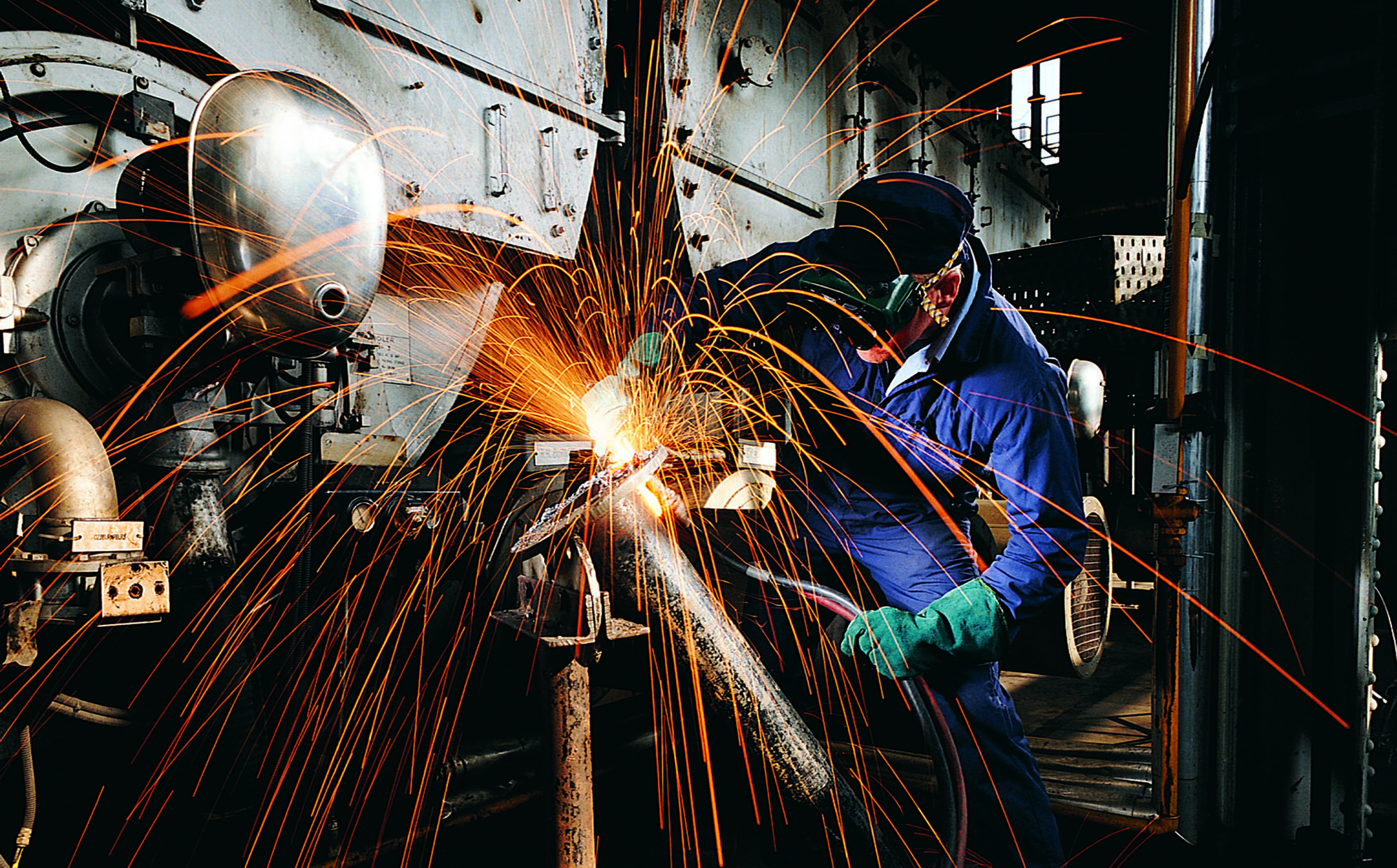 Man welding a pipe with lots of sparks flying