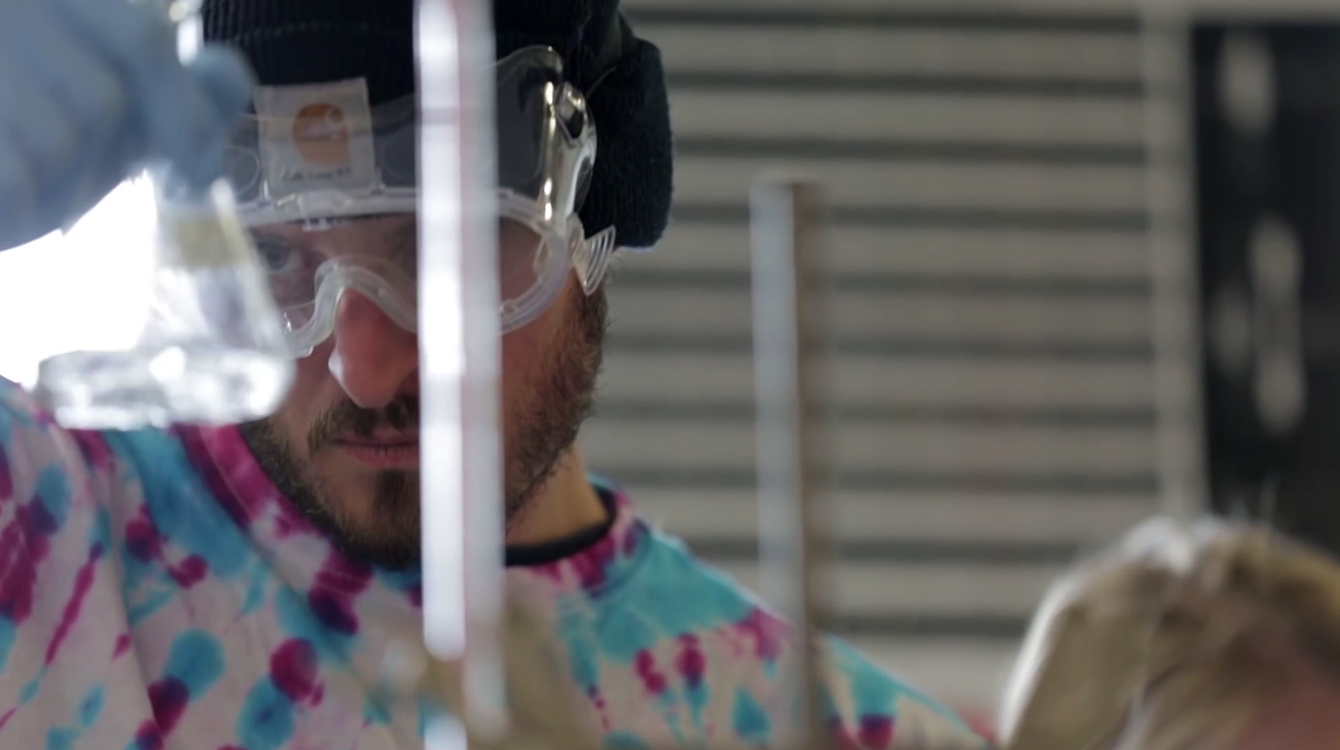 young man in chemistry glasses holding a beaker