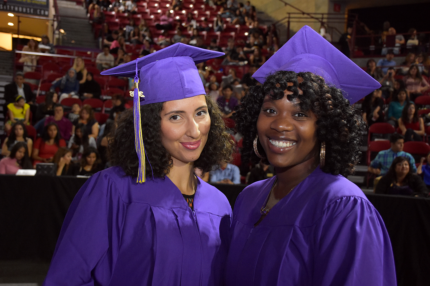 two females wearing cap and gowns at commencement