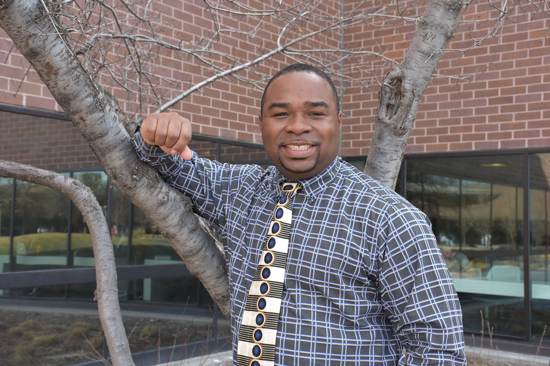 black man standing by a tree smiling