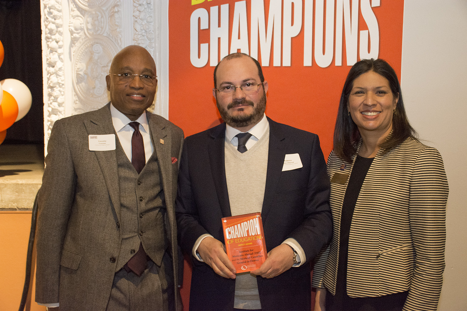 The Impact Champion was awarded to the Institute for Mexicans Abroad (IME) and the Consulate General of Mexico in Denver three people pose at an award function