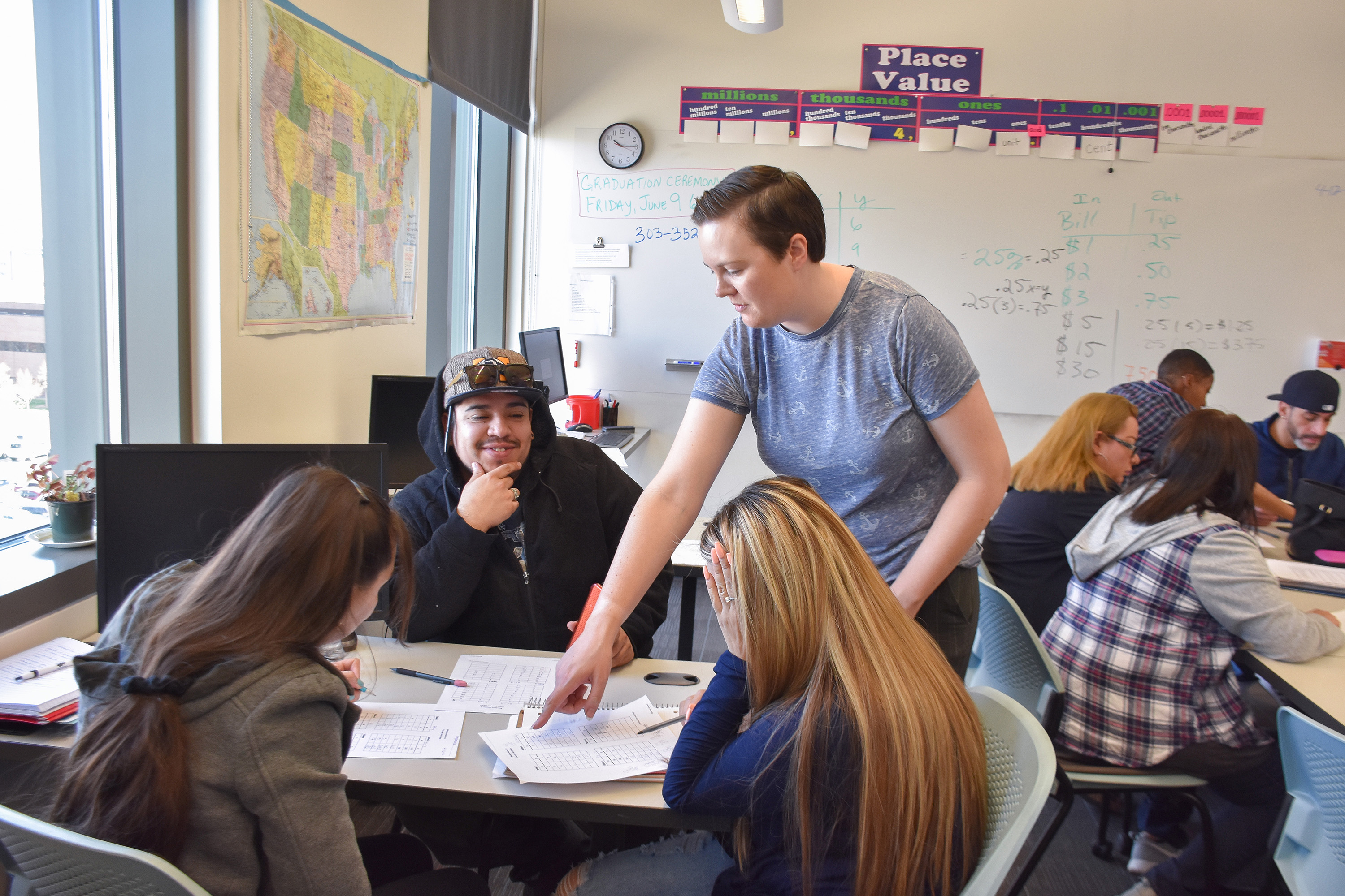 classroom of 3 students and a teacher working at a table