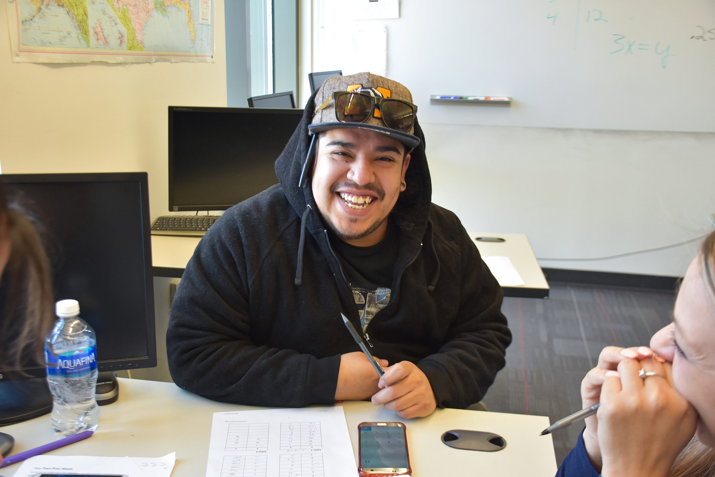 young man in a hat smiling holding a pencil