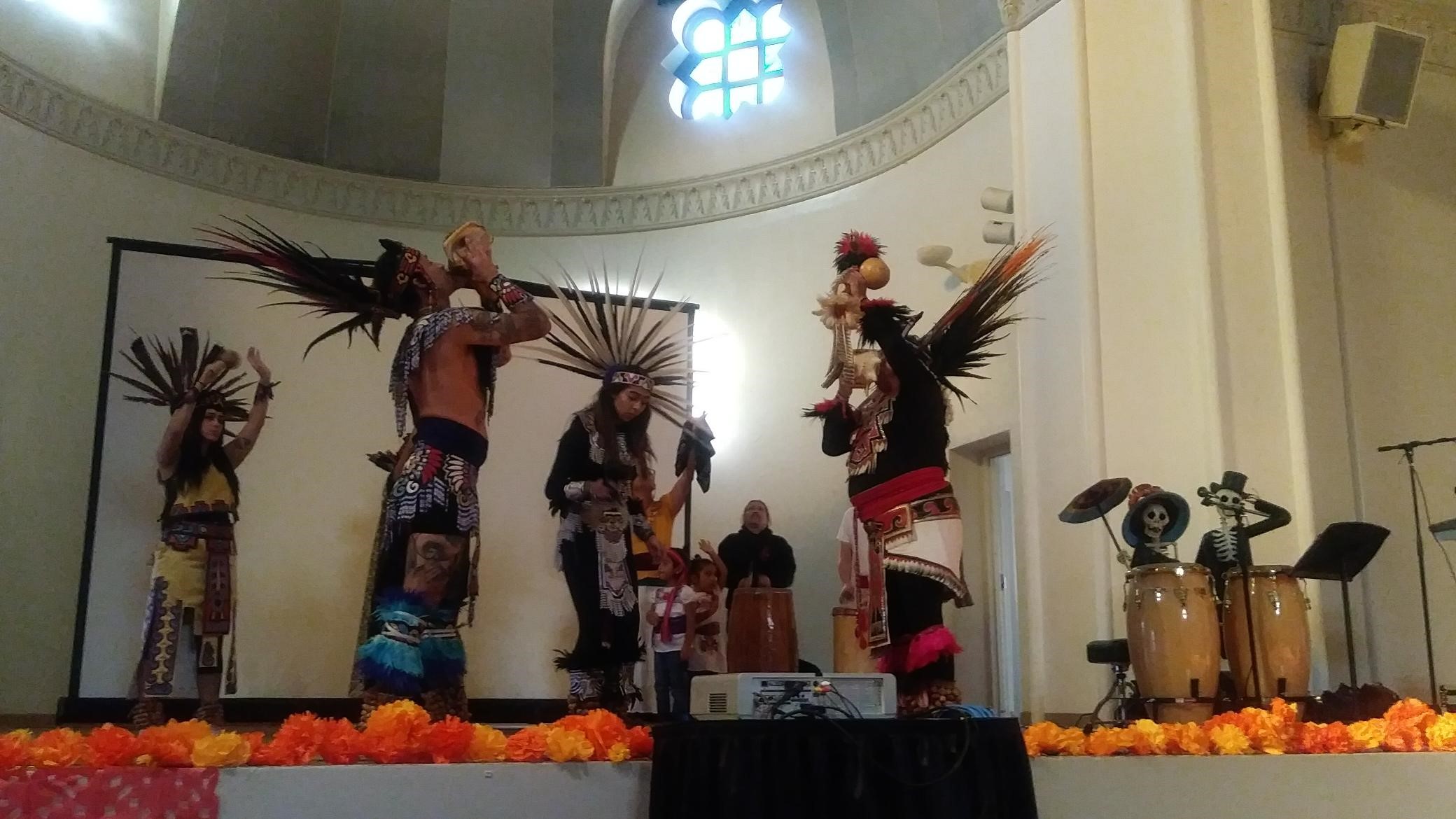 Huitzilopotchli Aztec Dancers in traditional wear, feathers in their hair and bells around their ankles. Drummers in back.