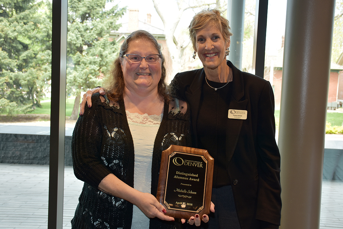 two women standing holding a plaque