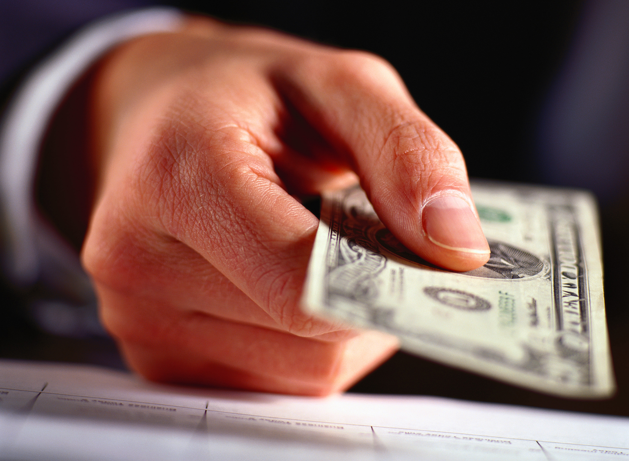 A close up of a hand holding a twenty dollar bill