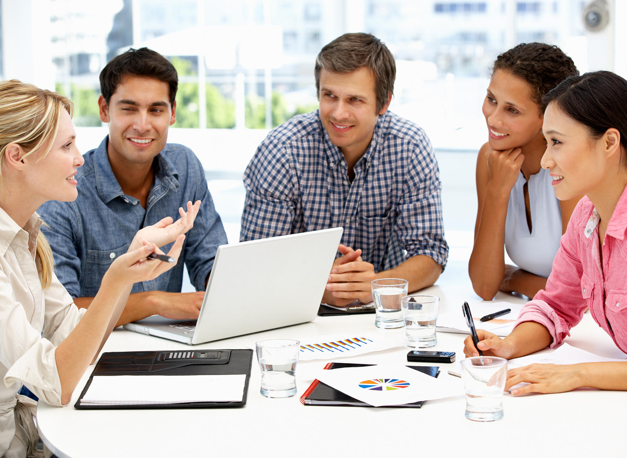 Five students talking around a laptop computer