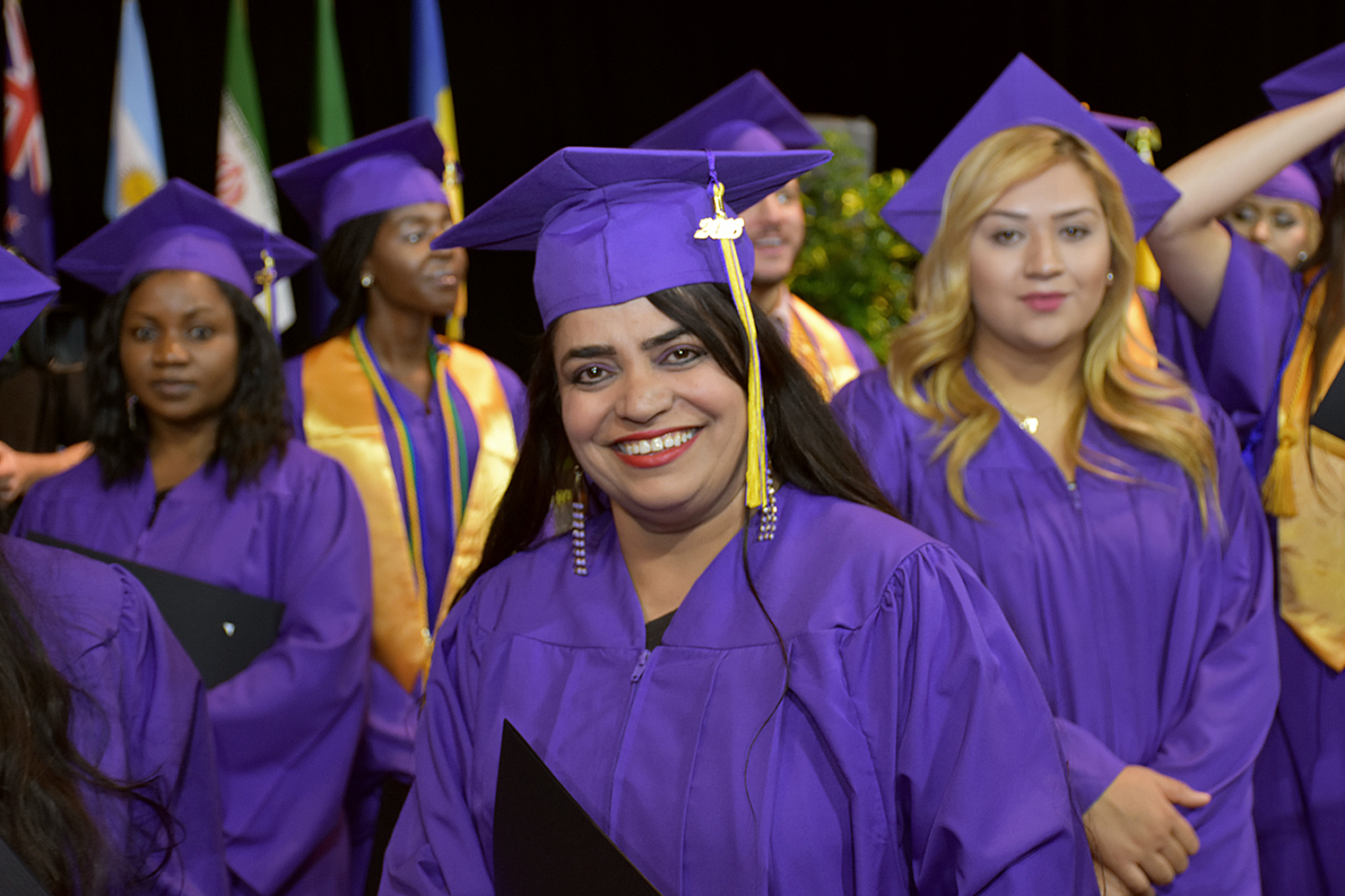 woman with purple cap and gown with other women in the background smiling