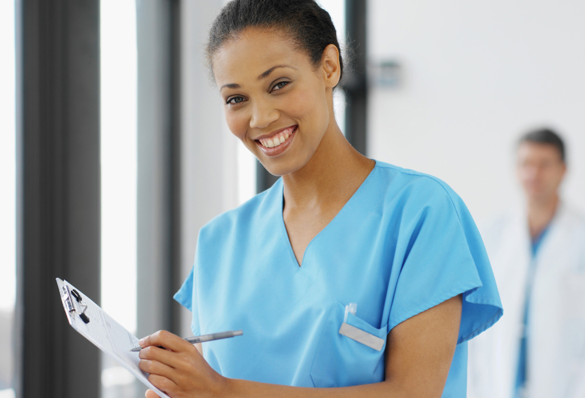 image of a young nurse wearing medical scrubs holding a clipboard