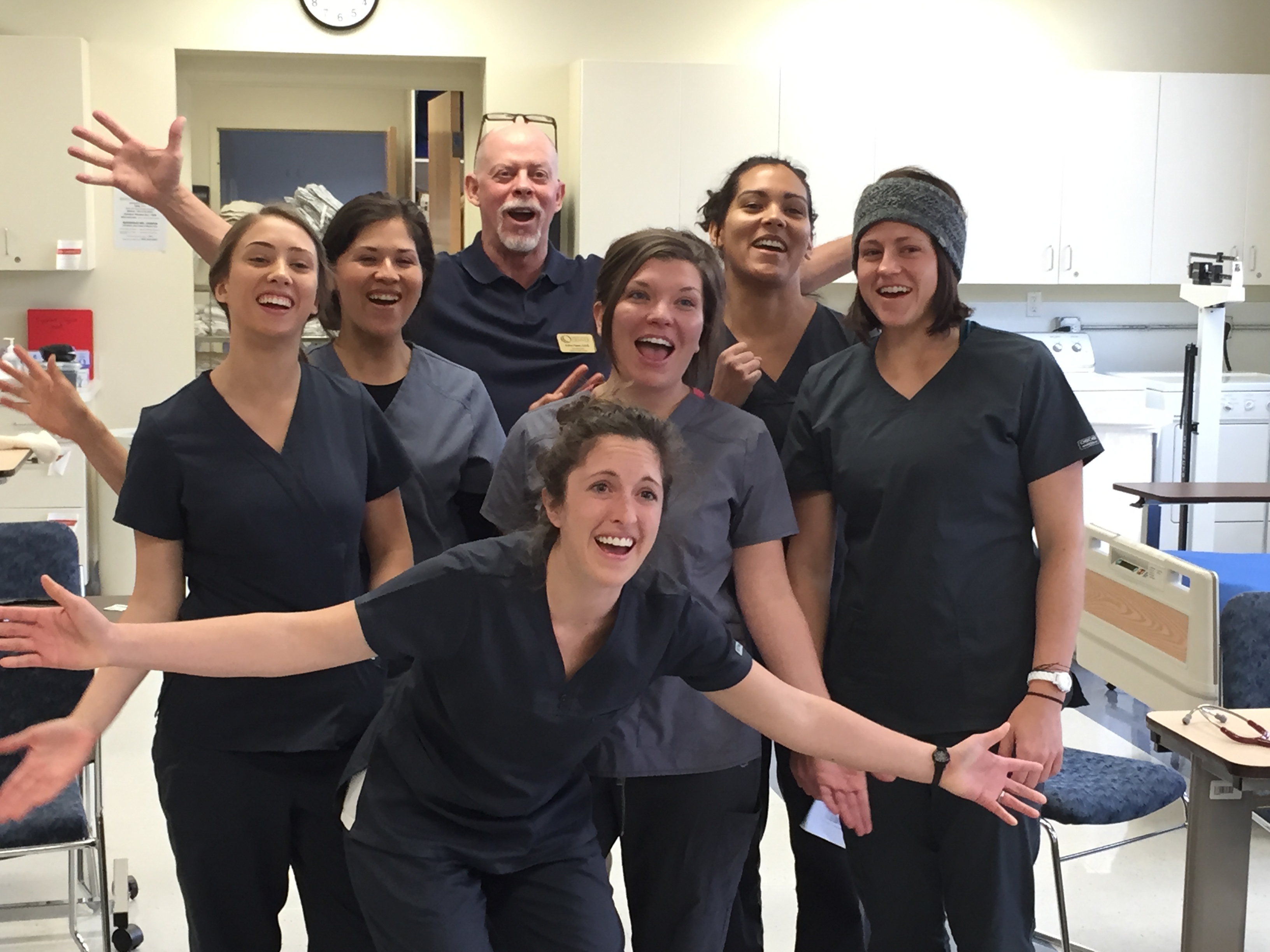 group of smiling nurse aide students smiling with their arms outstreched