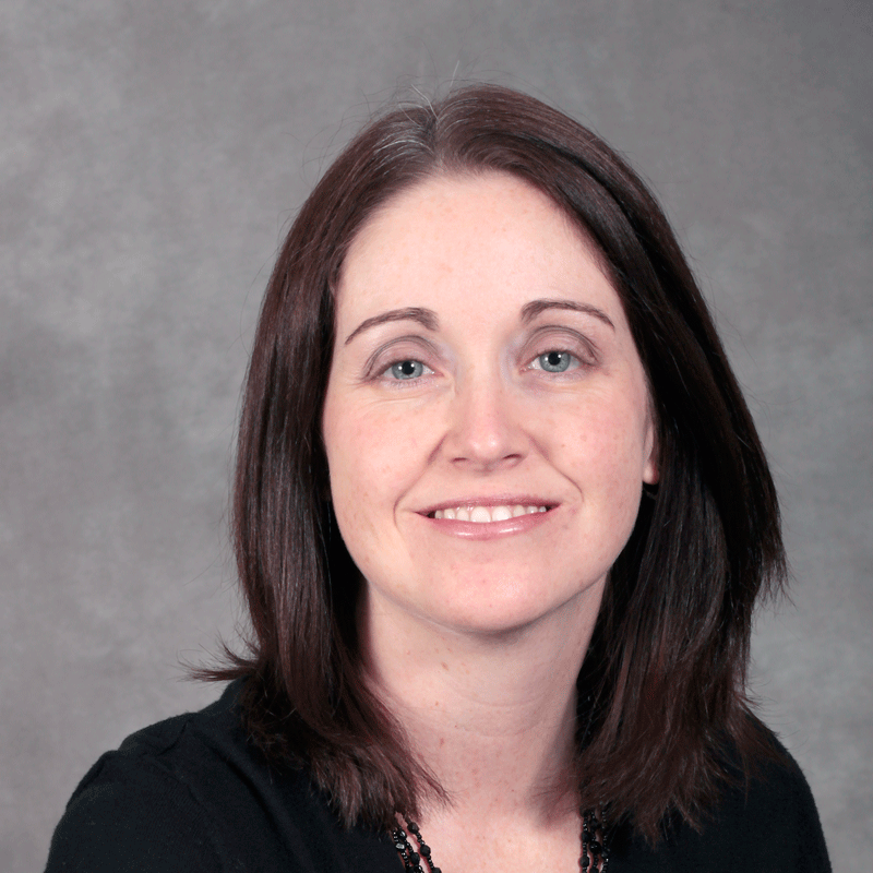 Smiling person with medium length dark brown hair wearing a black top