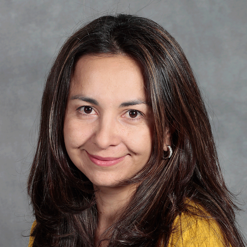 smiling woman with long dark brown hair wearing a gold top