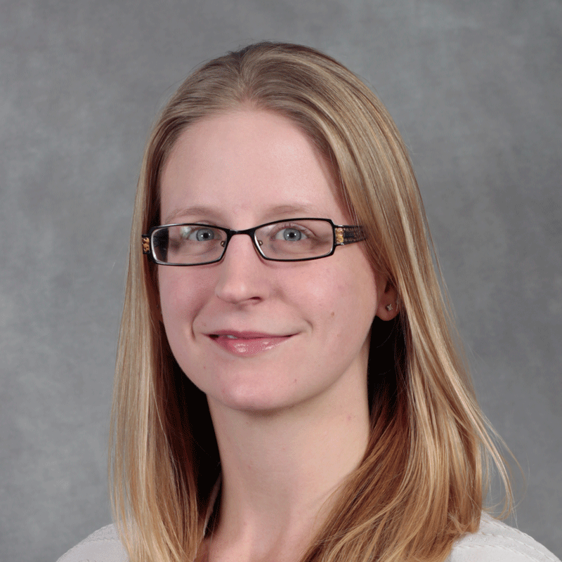 Person with medium length blond hair wearing glasses and white top