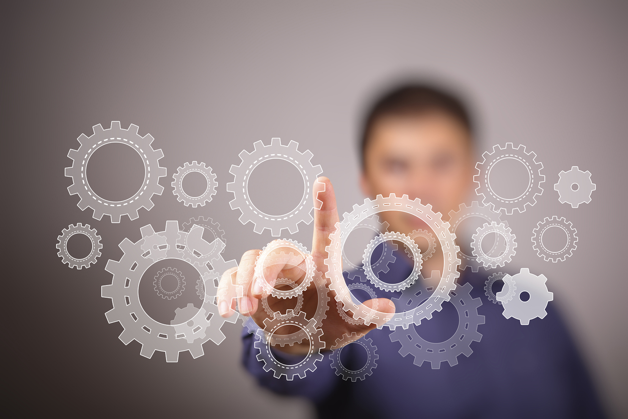 image of blurred male student reaching out to touch floating gears