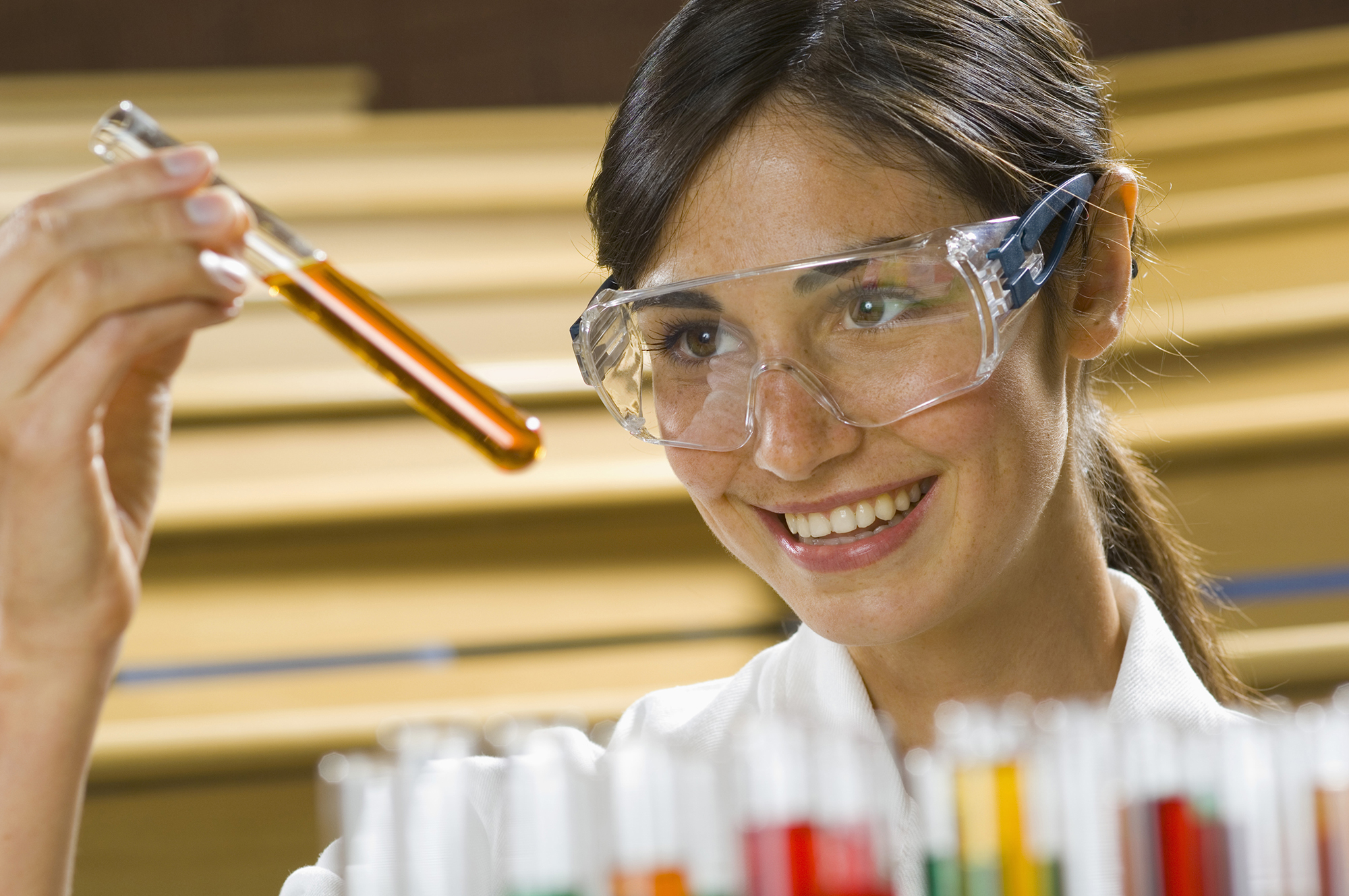 Female student looking at amber liquid in a test tube