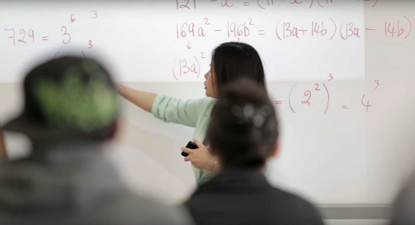 Math teacher at the white board pointing to math equations 