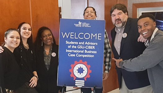Students and professors posing around a Welcome sign.