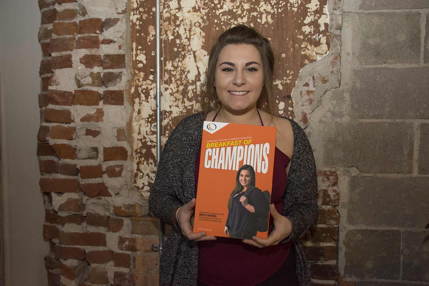 CCD Associate of Arts – Communication Student Molly Hayden, Kingdom Enlightenment Scholarship and Colorado Opportunity Scholarship Initiative young women holding box with her picture on it
