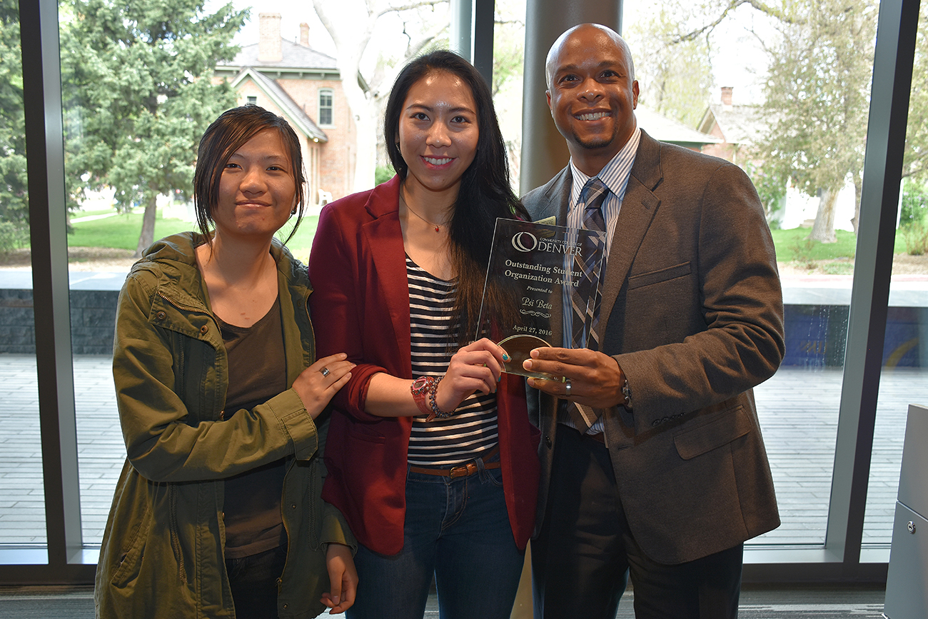 two women and a man standing holding a plaque