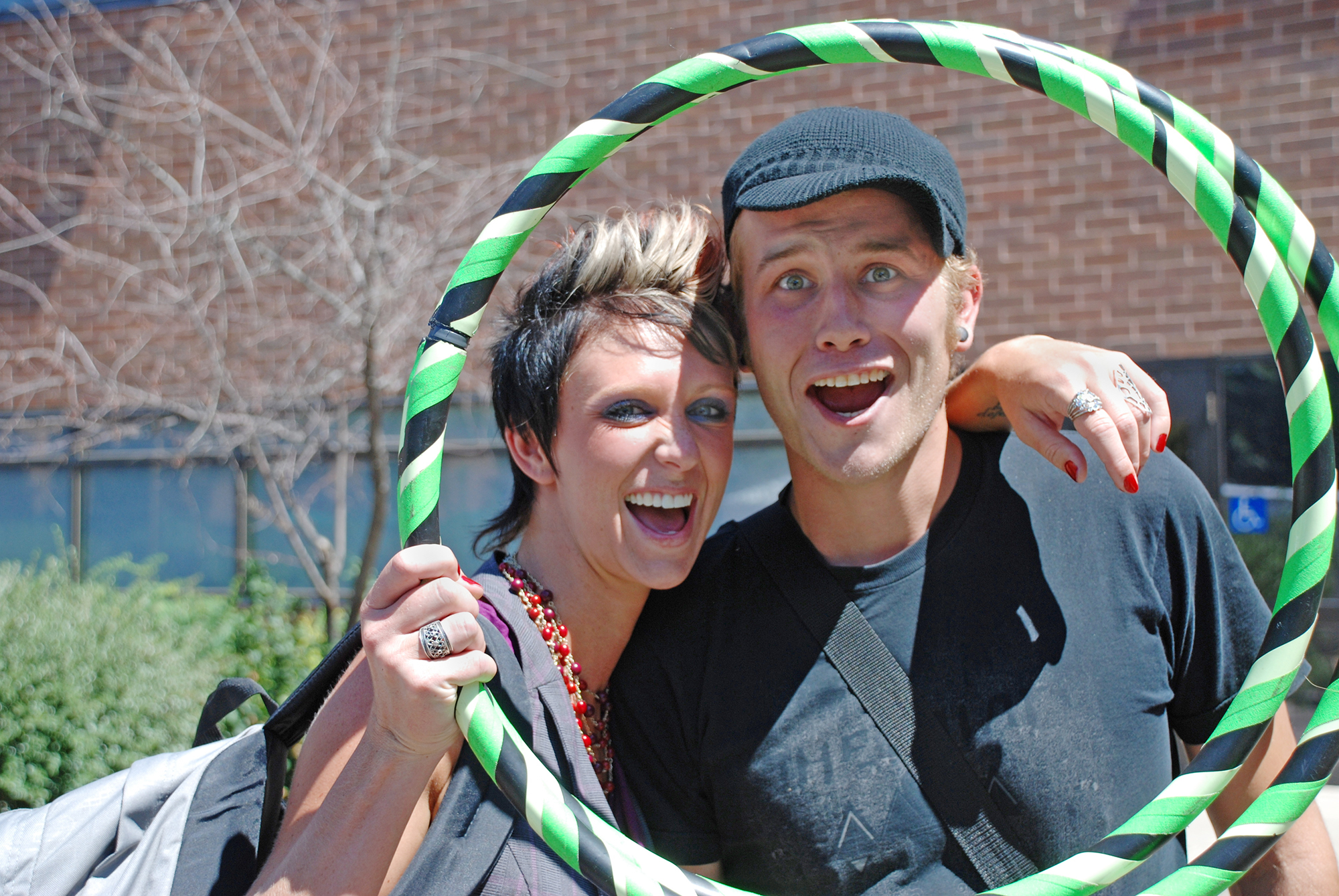 Female and male student smiling and looking through hula hoop