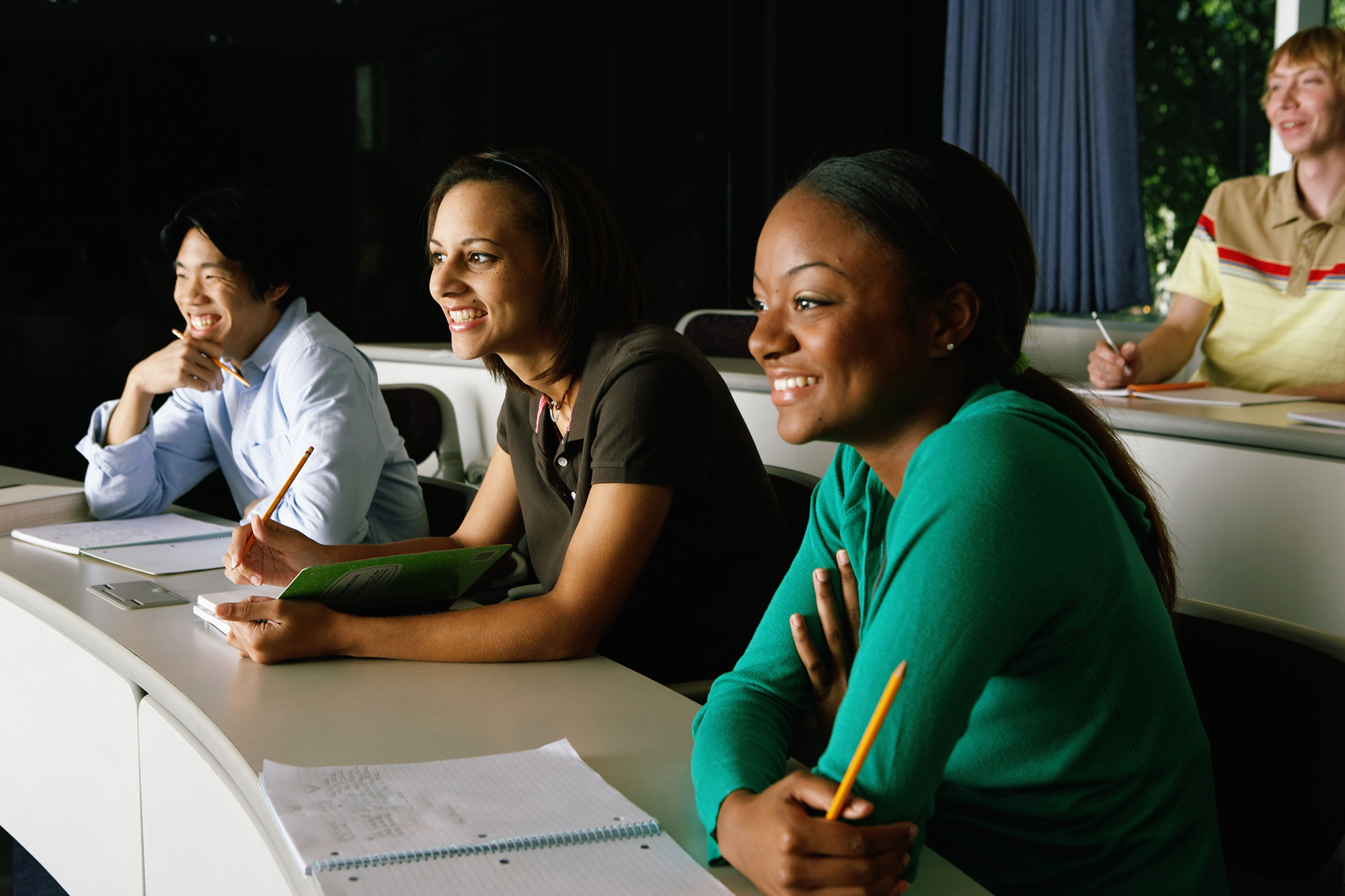 Four students smiling in a lecture hall setting